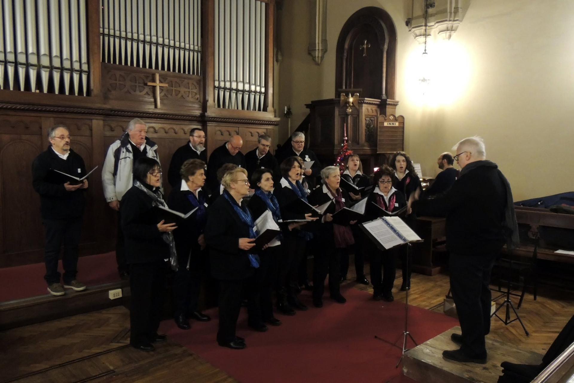 Il coro che canta durante un concerto natalizio in chiesa, con il maestro sul podio
