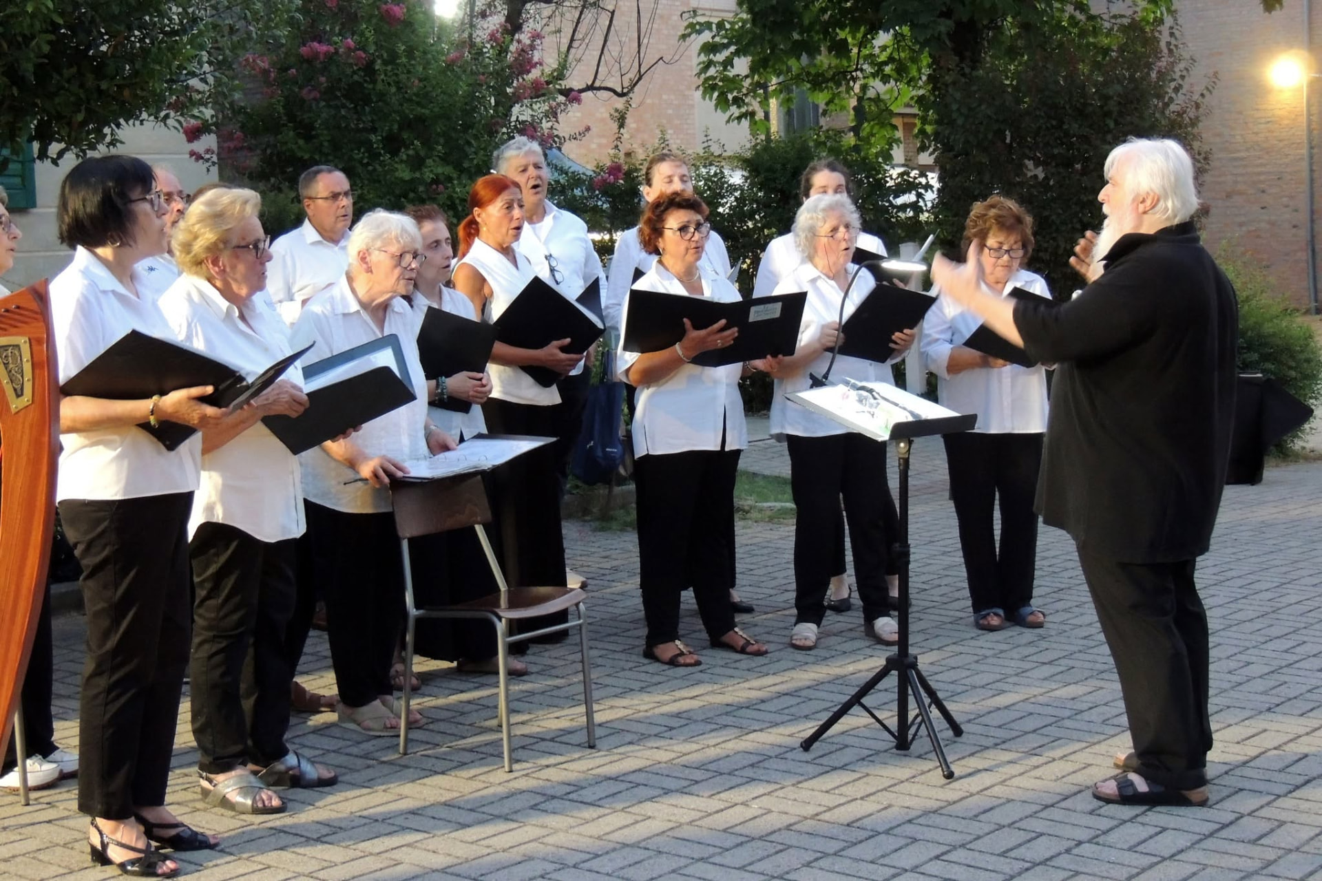 Il maestro dirige il coro in una corte all'aperto