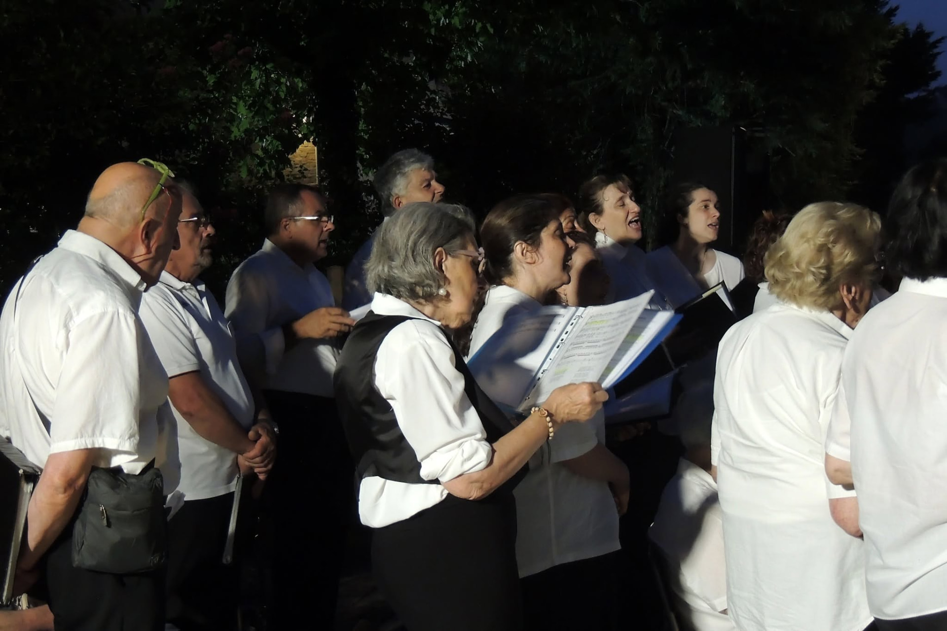 Le coriste cantano di notte, illuminate da una luce calda
