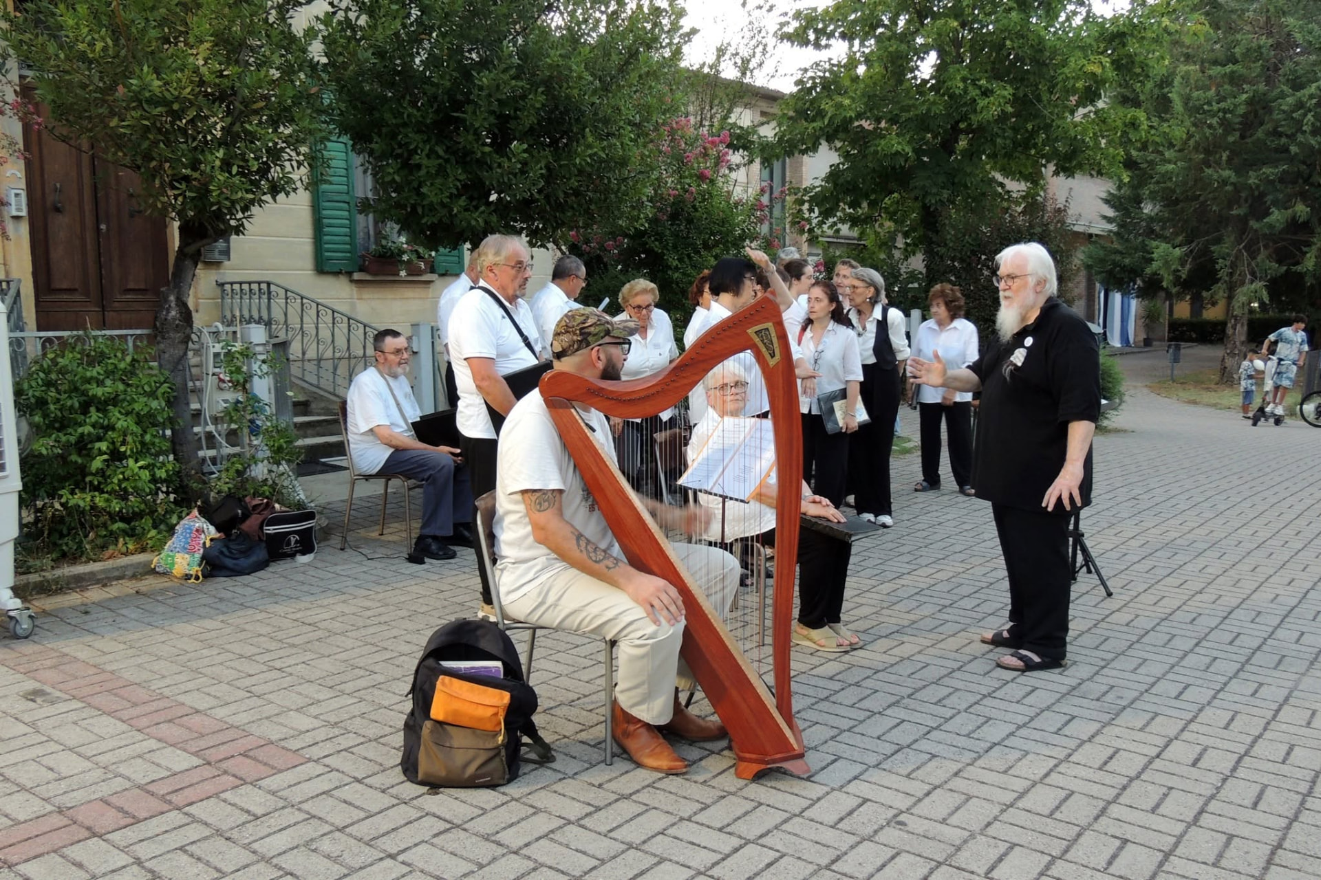Il coro con il maestro e l'arpa durante una serata estiva