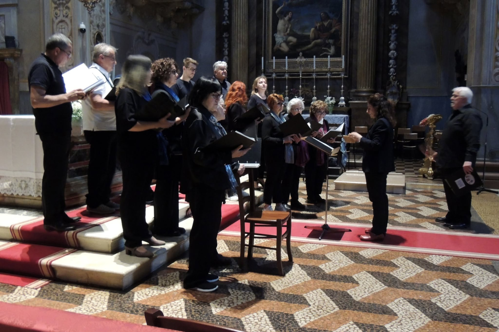 I coristi con i faldoni delle partiture cantano nella chiesa, accompagnati dal maestro