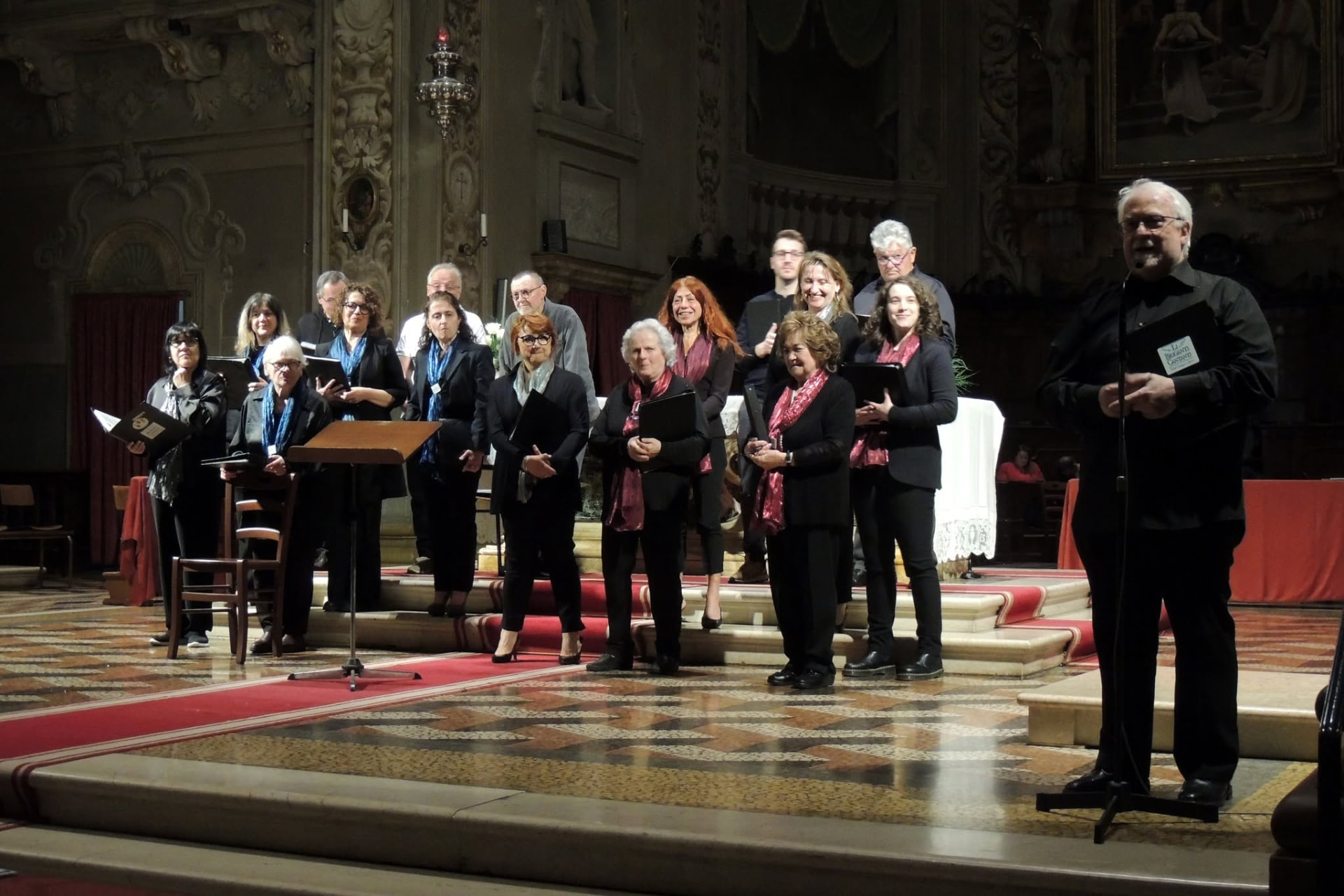 Il coro in concerto alla luce delle candele, con il maestro al microfono